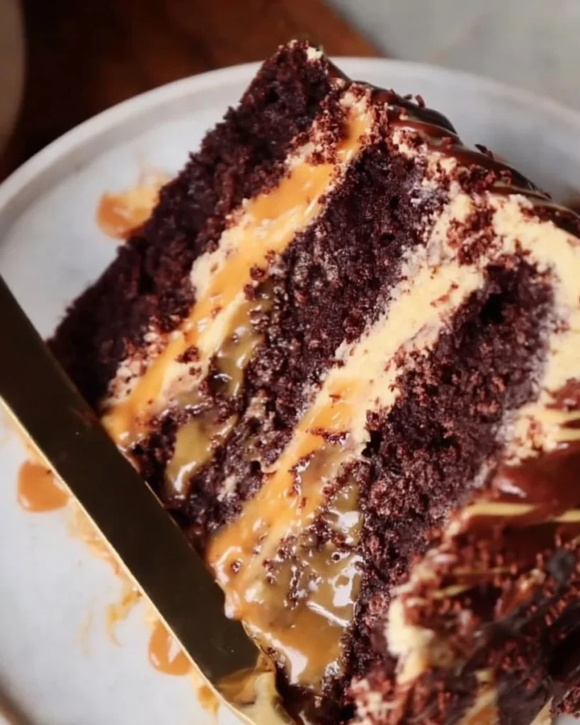 Delicious Chocolate Snickers Cake topped with chocolate, caramel, and peanuts.