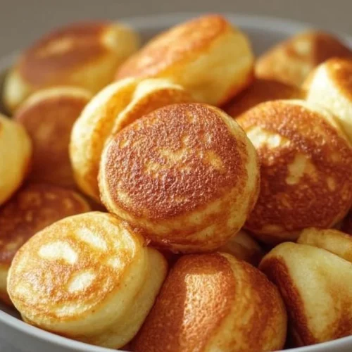 A plate of delicious breakfast pancake poppers topped with syrup and fruit.