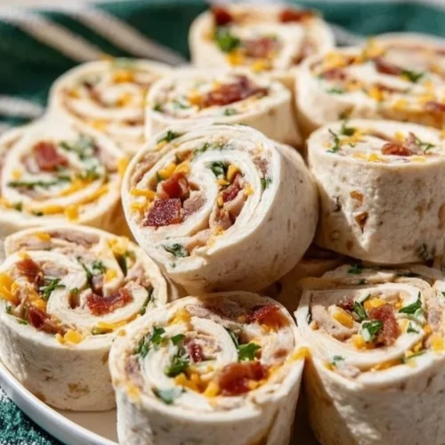 Savory Chicken Bacon Ranch Pinwheels topped with fresh herbs and served on a platter.