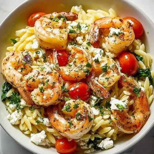 Plate of lemon feta orzo shrimp garnished with fresh herbs