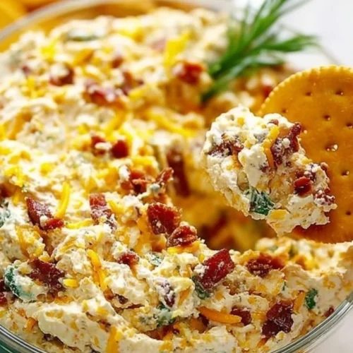 Delicious Million Dollar Dip served in a bowl with crackers and vegetables.