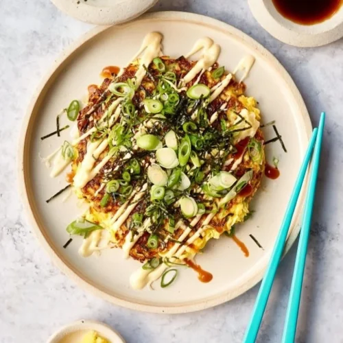Vegan Okonomiyaki topped with fresh vegetables and sauces