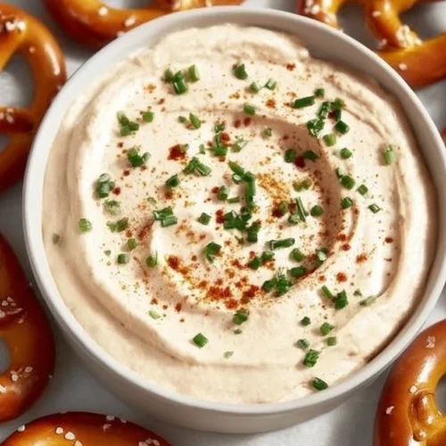 Creamy and cheesy pretzel dip served in a bowl with pretzels on the side