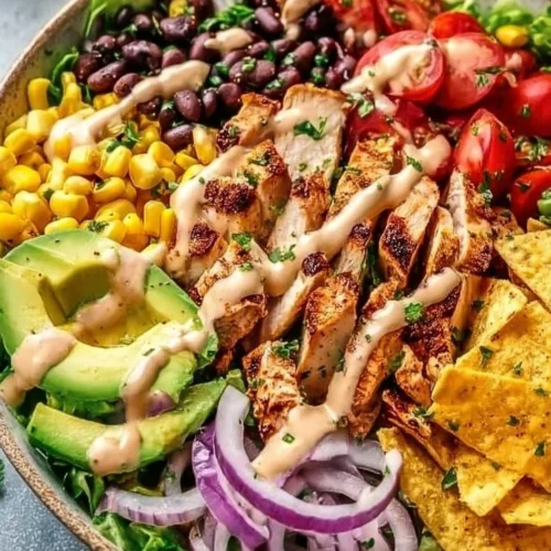 Bowl of spicy avocado salad with colorful vegetables and dressing