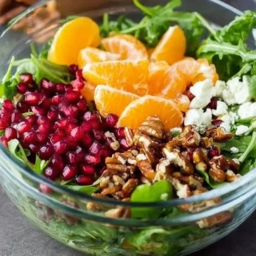 A colorful winter salad featuring seasonal greens, fruits, and nuts.