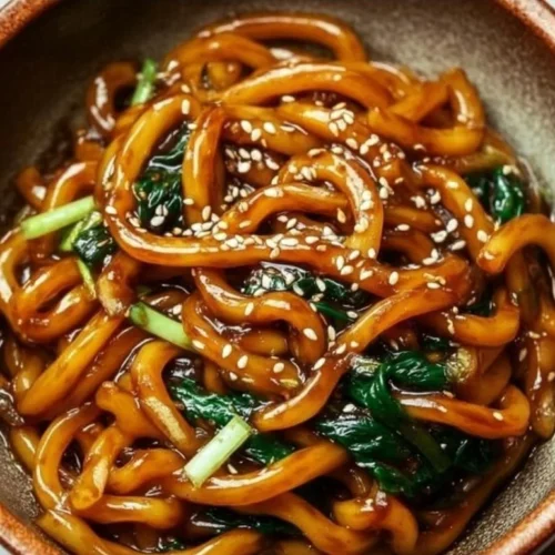 A colorful bowl of homemade Yaki Udon noodles with vegetables and sauce.