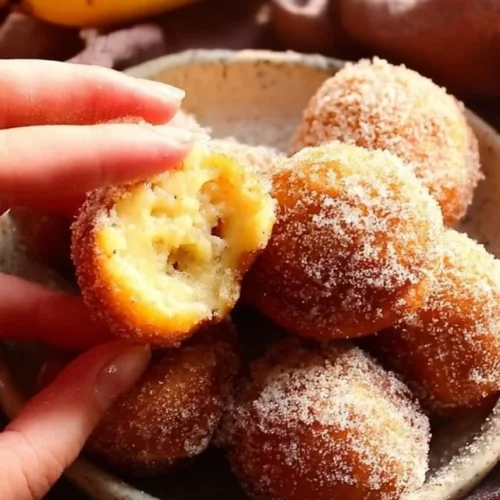 Air fryer banana donut holes served on a plate with powdered sugar topping.