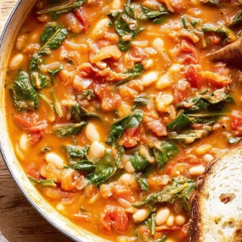 Creamy vegan tomato white bean stew in a bowl, garnished with herbs