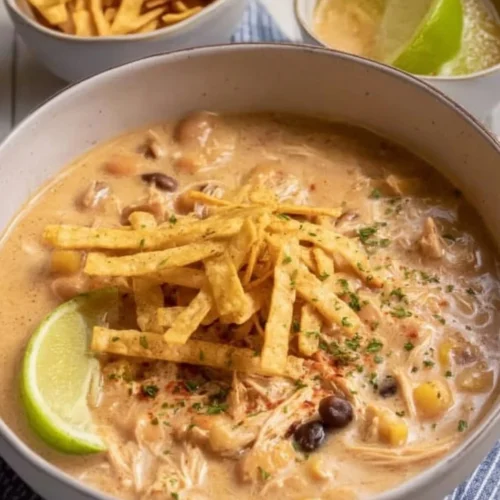Crockpot White Chicken Chili with Cream Cheese in a bowl topped with herbs
