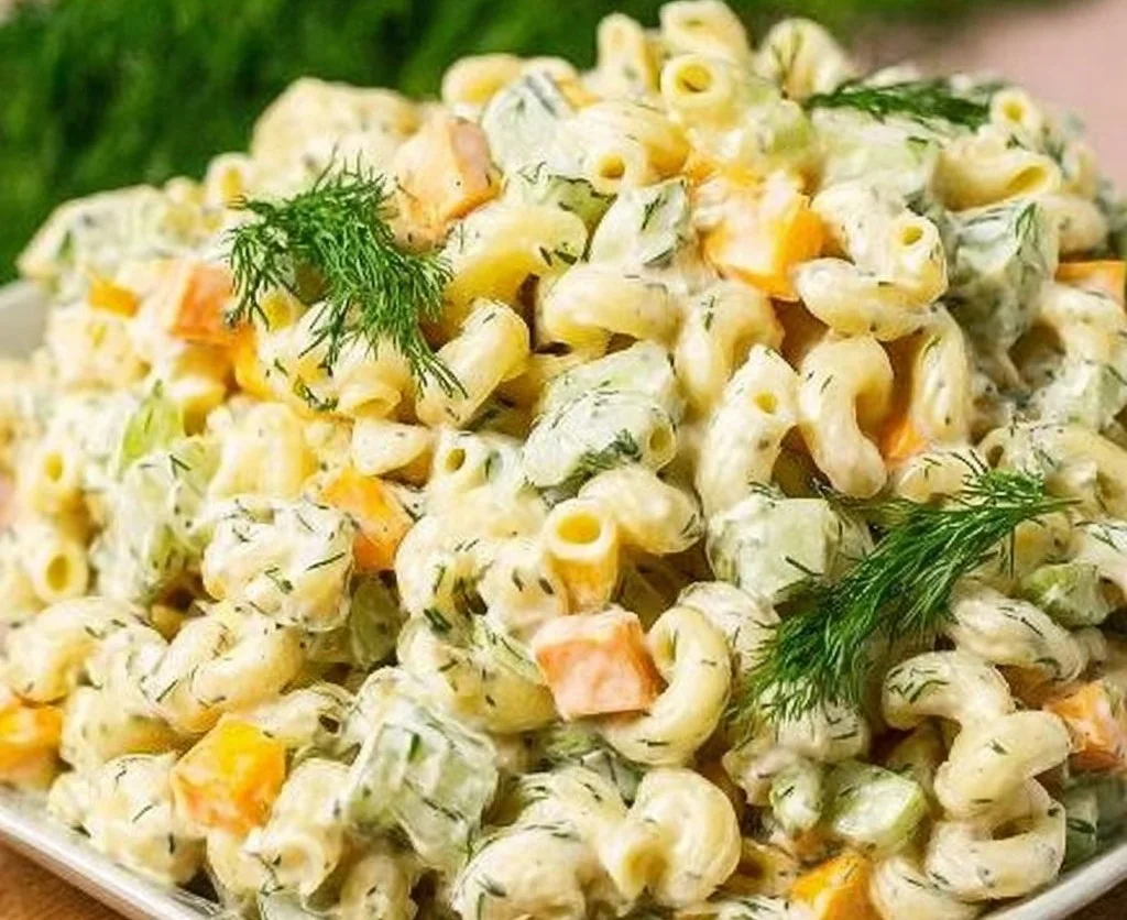 Delicious dill pickle pasta salad served in a bowl with fresh herbs and vegetables.