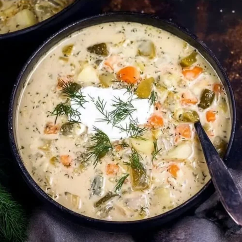 A bowl of creamy Dill Pickle Soup garnished with fresh herbs