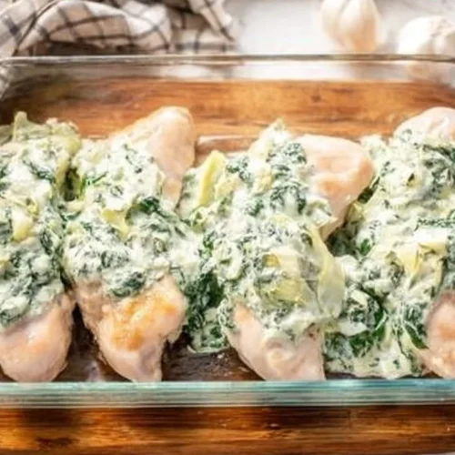Healthy spinach artichoke chicken bake dish on a plate, garnished with herbs.