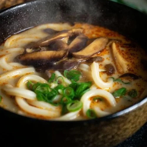 Bowl of miso udon noodle soup garnished with green onions and tofu