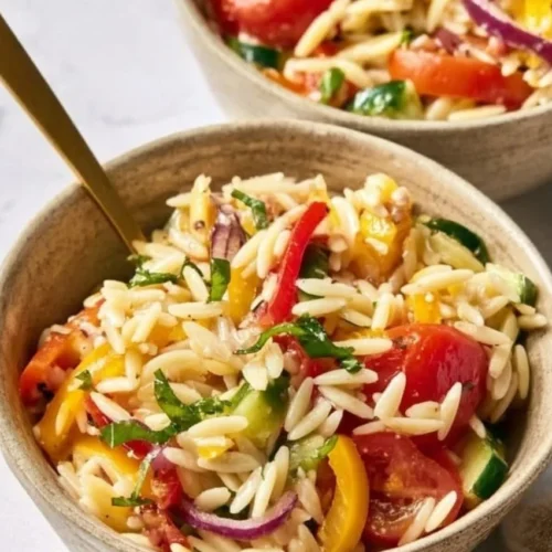 Delicious orzo salad with colorful vegetables and dressing.