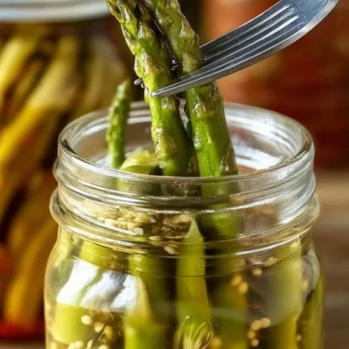 A jar of spicy pickled asparagus ready to serve as a flavorful snack or garnish.