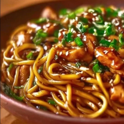 Sticky garlic chicken noodles served in a bowl with fresh herbs