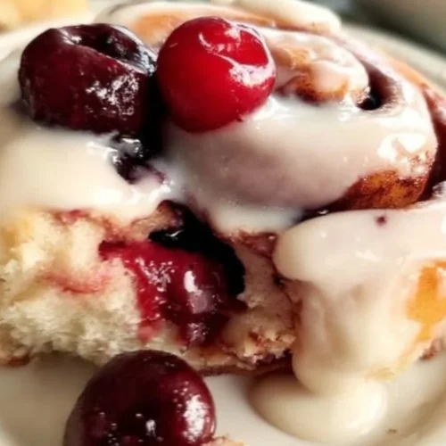 Freshly baked Cherry Cinnamon Rolls drizzled with icing on a plate