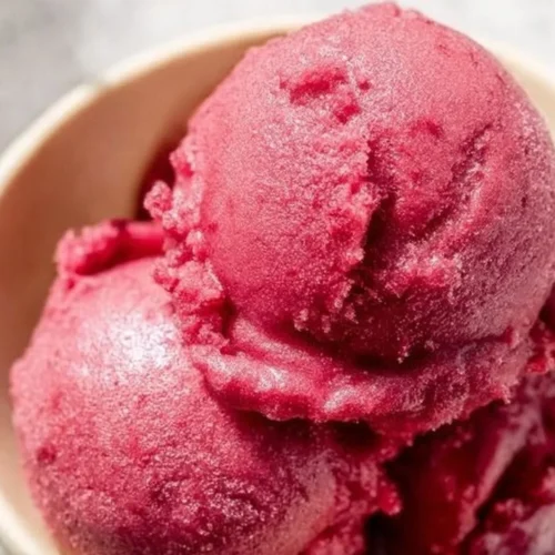 Bowl of vibrant cherry sorbet topped with cherries and mint leaves
