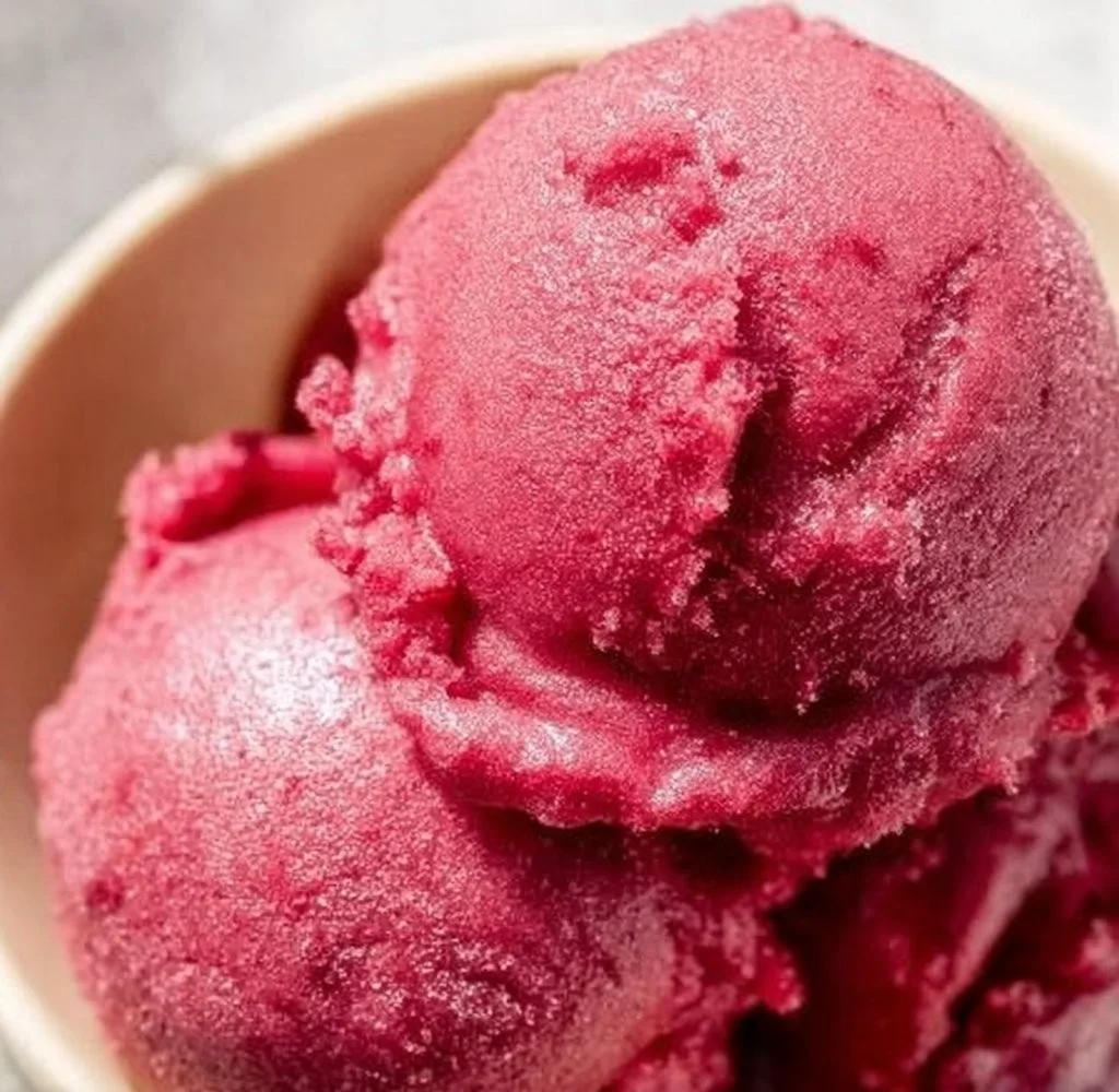 Bowl of vibrant cherry sorbet topped with cherries and mint leaves