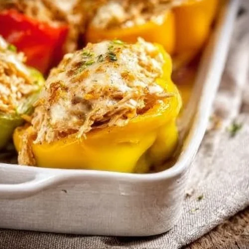 Creamy chicken stuffed peppers on a plate, garnished with herbs.