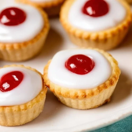 Mini Cherry Bakewell Tarts topped with icing and cherries.