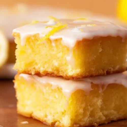 Delicious viral lemon brownies with bright yellow frosting and dusting of powdered sugar.