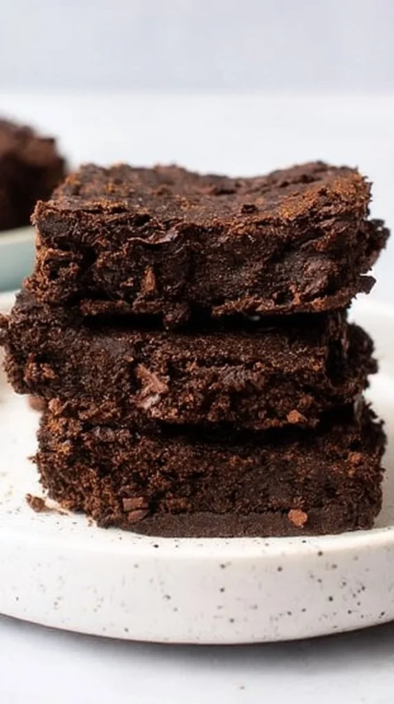 Delicious and healthy black bean brownies on a white plate with chocolate drizzle
